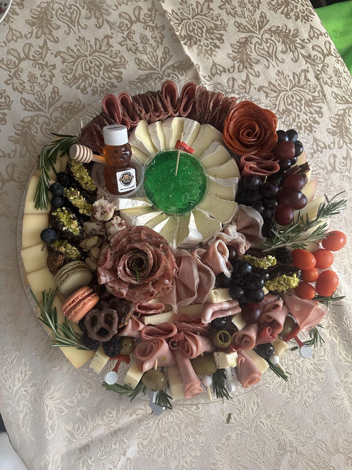 Round charcuterie board with honey jar and salami roses