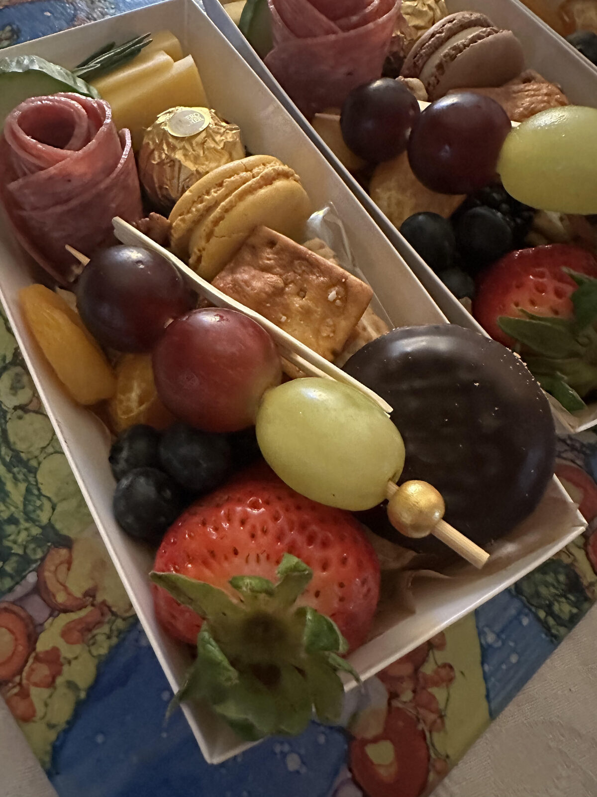 Two personal boxes with fruit skewers and macarons